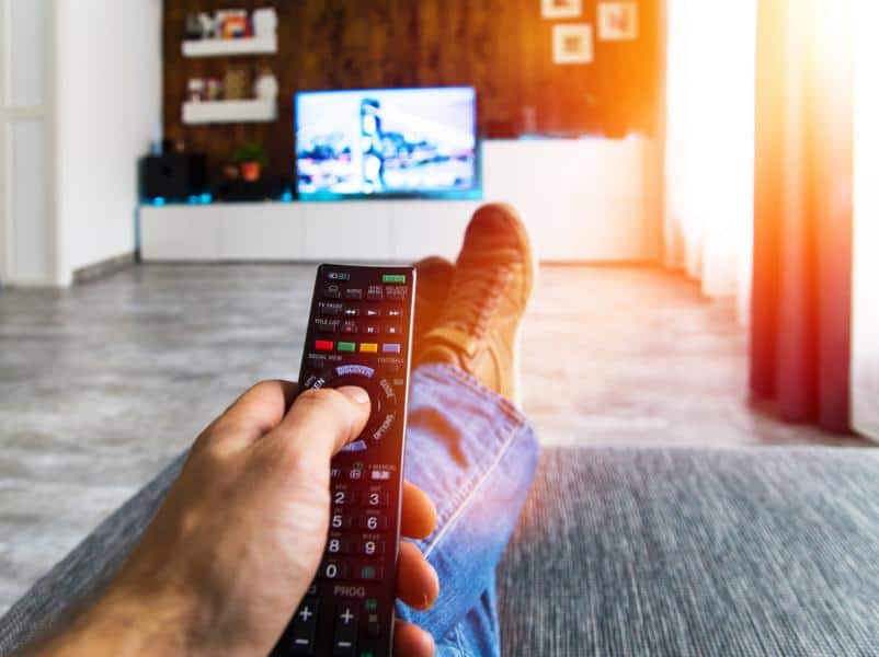 Zappen / Fernsehen auf der Couch mit Fernbedienung in der Hand
